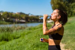 female in the sun tanning with new tattoos drinking water